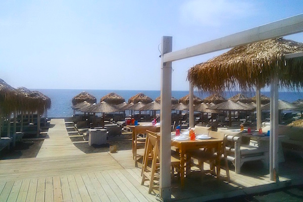 Umbrellas, chaises and terrace dining at Santorini's black sand beach